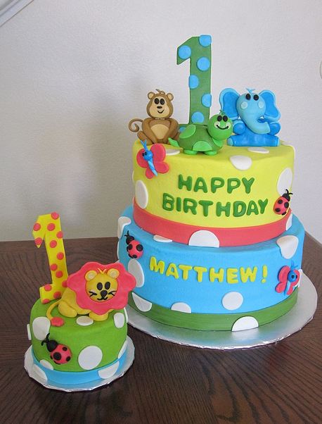 Two tier Safari theme first birthday cake with animals and matching mini cake
